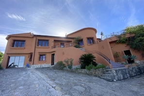 A two-story house with a stone facade, multiple windows, and a curved staircase leading to the entrance. - Pretty, luxurious villa with private pool and superb view (Dénia)