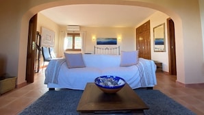 A bedroom with a large bed, a wooden table with a bowl, and a view of the sea through the window. - Pretty, luxurious villa with private pool and superb view (Dénia)