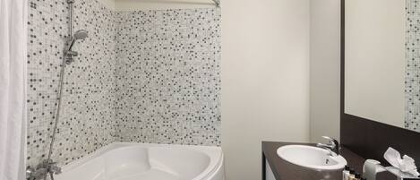 Une salle de bain moderne avec un mur de douche recouvert de mosaïques, une baignoire sur pieds et un meuble-lavabo avec un miroir.