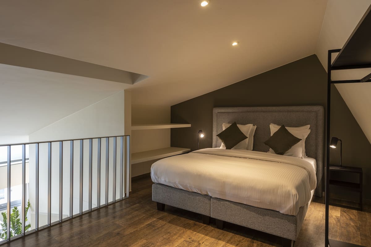 Quarto moderno com uma cama grande, varanda e escada.