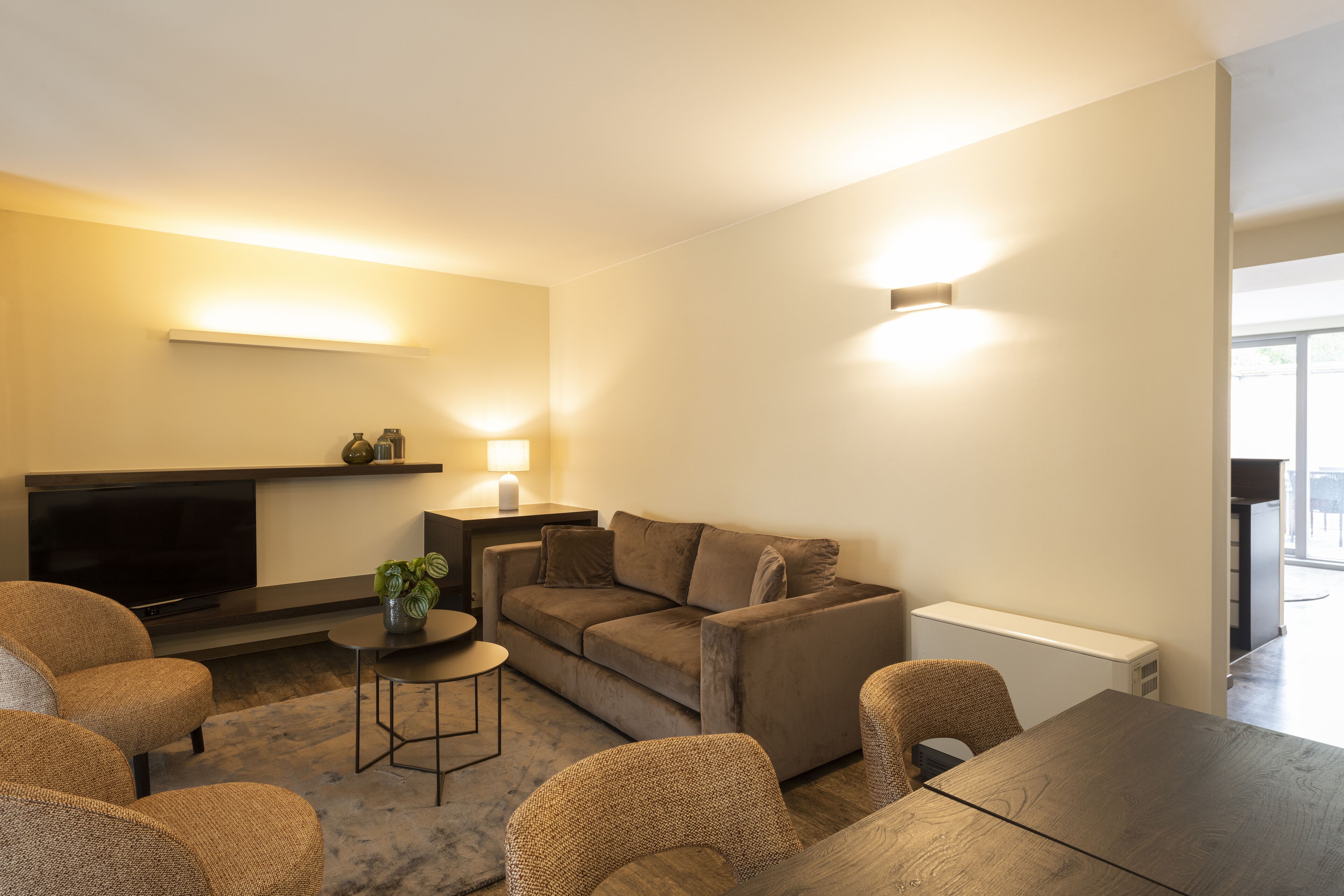 Un salon moderne comprenant un canapé, des fauteuils, une table basse, un téléviseur à écran plat et une cheminée.