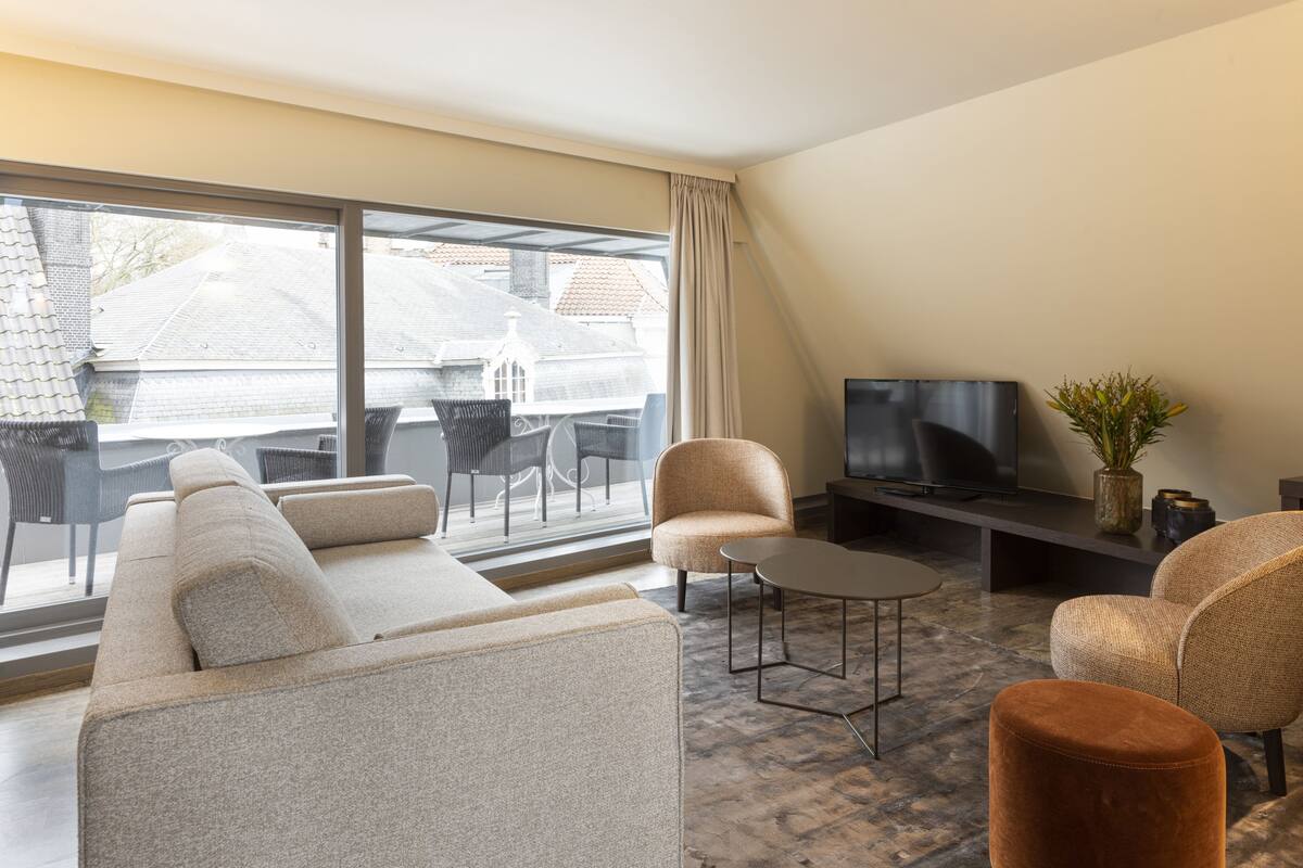 Uma sala de estar moderna com sofá, cadeiras, mesa de centro e televisão.