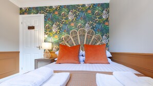 Una habitación de hotel con una cama, dos almohadas, una mesita de noche y una lámpara.