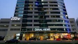 Un hotel de varios pisos con fachada curva, que presenta un letrero llamativo que dice 'CANAL VIEWS' a nivel del suelo, indicando vistas al canal.