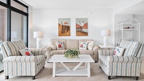 A living room with striped armchairs, a sofa, a white coffee table, and two wall-mounted lamps.