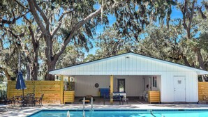 A pool area with a covered seating area, a table, and chairs. - Less than 1/2 mile to beach. Community pool. (St. Simons Island)