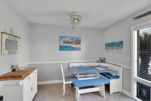 A room with a white bench, a small table, and a painting of a beach scene. - Less than 1/2 mile to beach.  Community pool. (St. Simons Island)