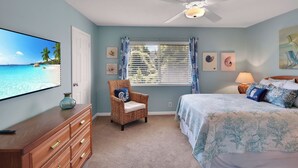 A bedroom with a bed, a chair, a TV, and a window with curtains. - Less than 1/2 mile to beach. Community pool. (St. Simons Island)