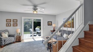 A modern living room with a staircase, a ceiling fan, and a view to a patio area. - Less than 1/2 mile to beach. Community pool. (St. Simons Island)