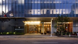 A JW Marriott hotel with a modern glass facade, outdoor seating area, and well-lit entrance. - JW Marriott Dallas Arts District Hotel (Dallas)