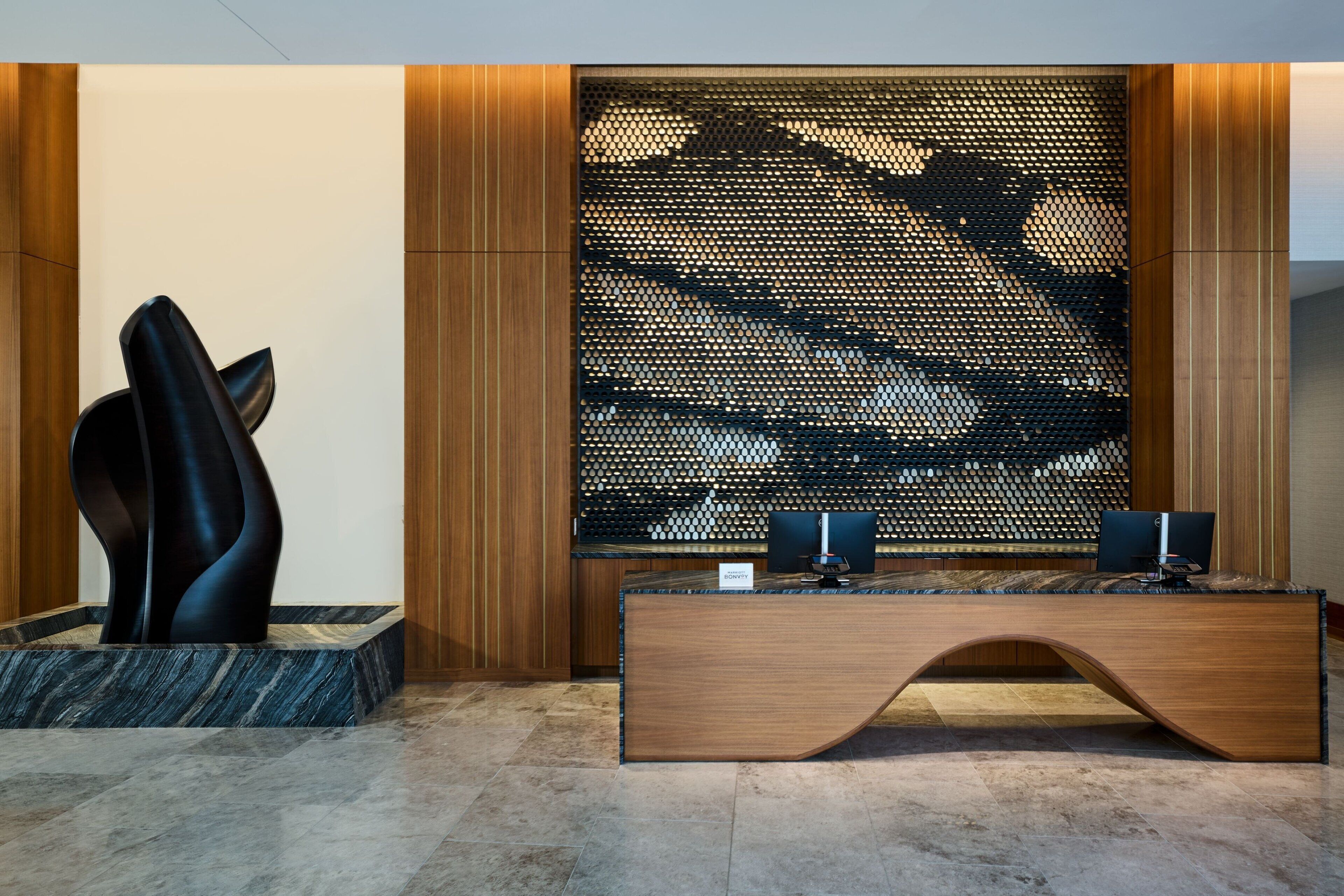 Una recepción de diseño moderno, un área de descanso con una silla original y un panel decorativo en la pared.