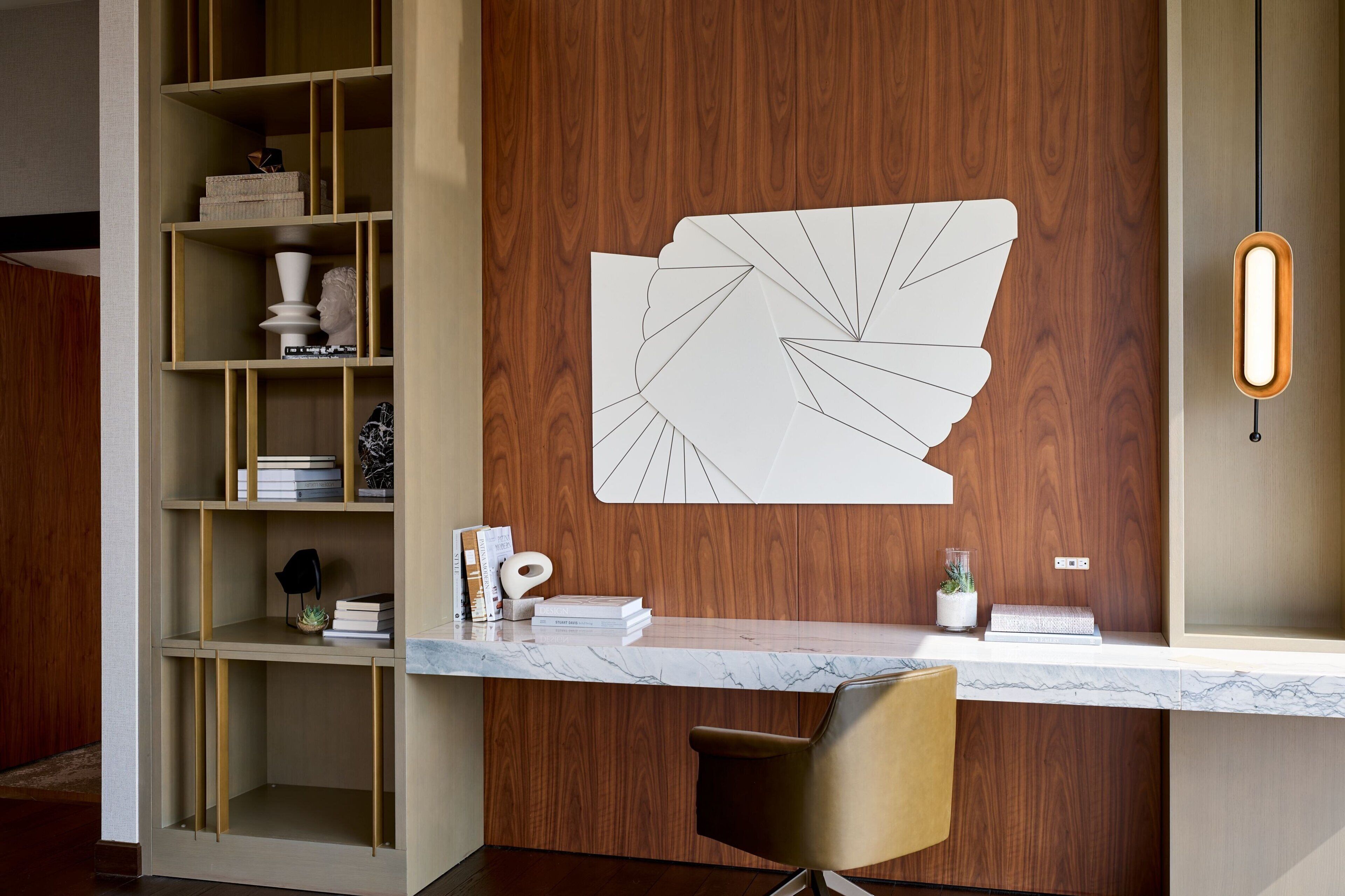 A modern reception desk with a wooden backdrop, a marble countertop, and a unique abstract wall art piece.