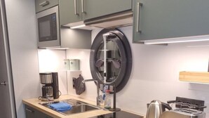 Eine moderne Küche mit grauen Schränken, einer Holz Arbeitsplatte, einem Spülbecken, einem Wasserkocher, einem Toaster und einer Mikrowelle.