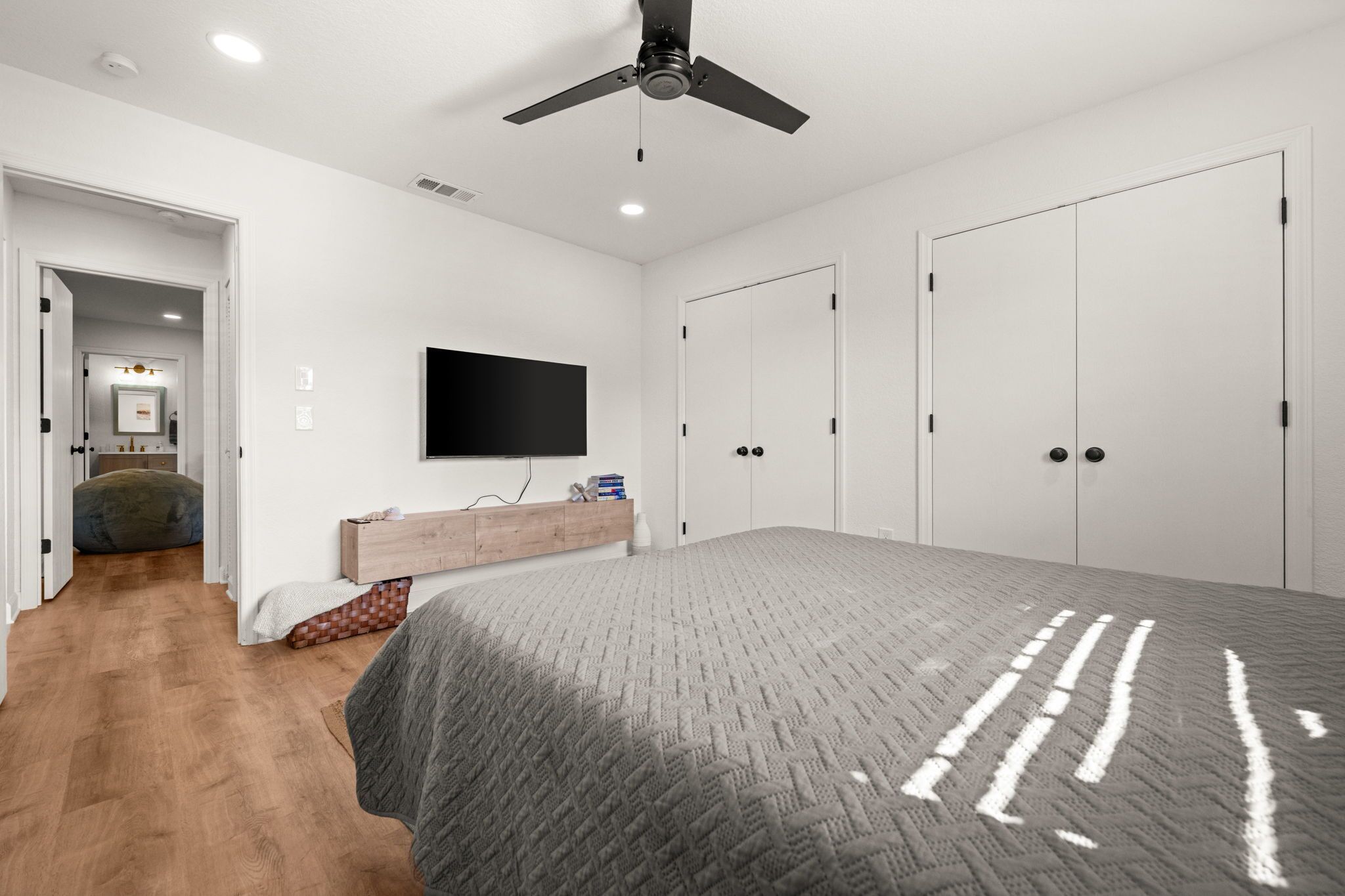 A bedroom with a bed, a ceiling fan, a TV, and a wardrobe.