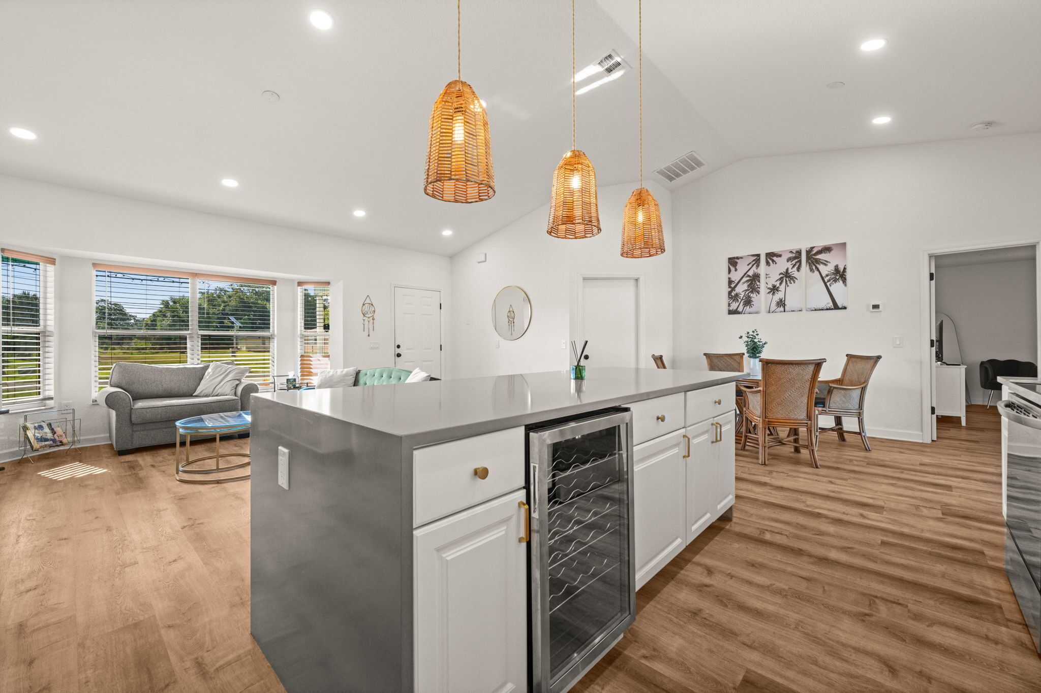 A modern kitchen with a central island, pendant lights, and a dining area with chairs.