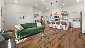 Ein modernes Wohnzimmer mit einem grünen Sofa, einem runden Spiegel und einem Glastisch.