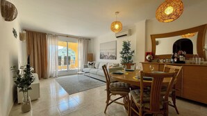 Una sala de estar moderna con comedor, ventanas amplias y vistas al exterior.