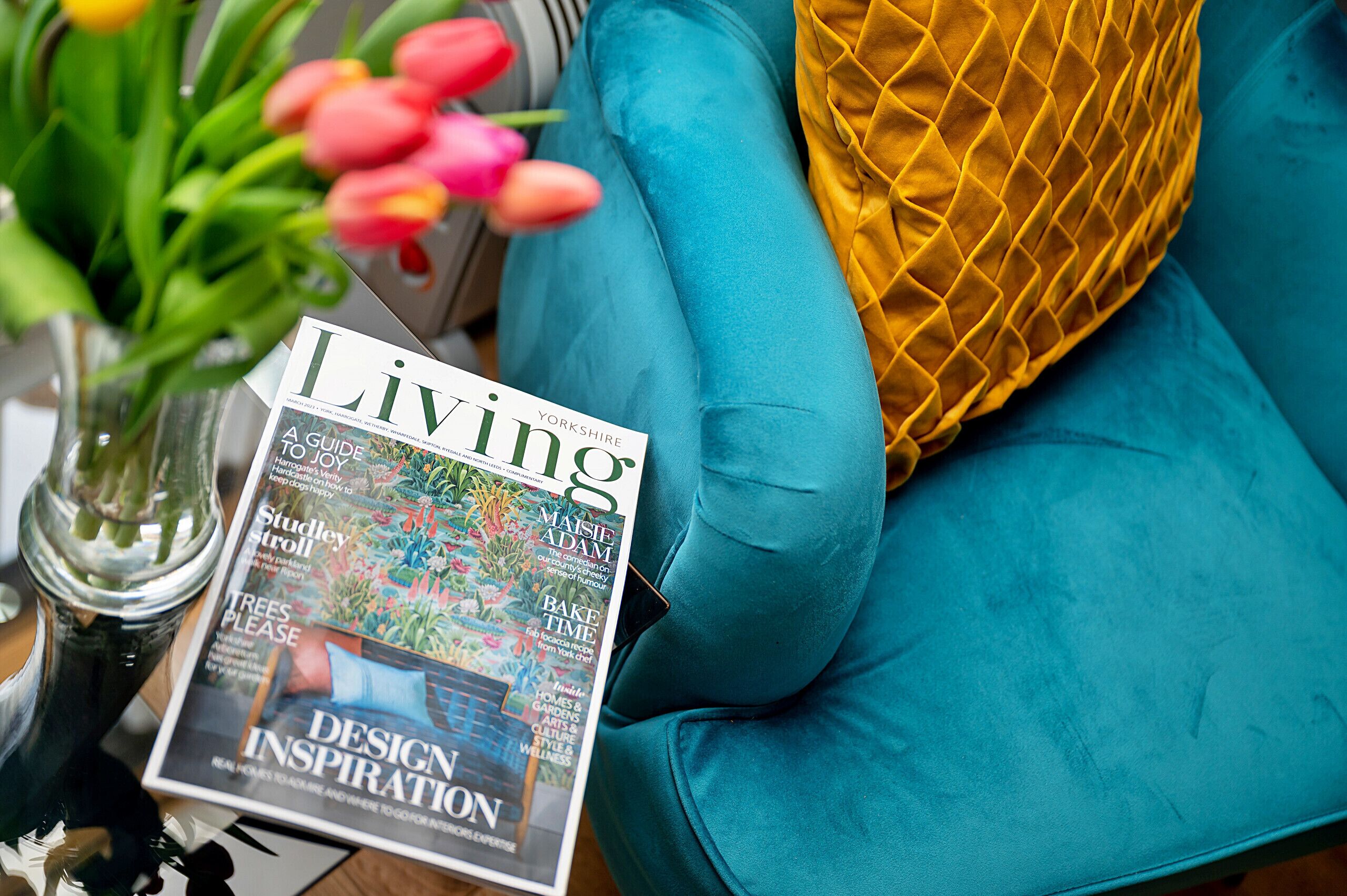 A magazine titled 'Living' on a teal sofa with a yellow pillow.