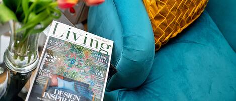 A magazine titled 'Living' on a teal sofa with a yellow pillow.