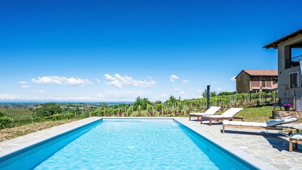 Ein rechteckiger Swimmingpool mit klarem, blauem Wasser, umgeben von Liegestühlen und einer Steindeck.