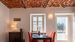 Ein Essbereich mit Ziegeldecke, einem Tisch mit vier roten Stühlen, einer Lampe und einem Fenster mit Blick auf Bäume.