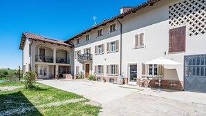 Ein zweistöckiges Gebäude mit Innenhof, inklusive Balkon, Sitzgelegenheiten im Freien und Garage.