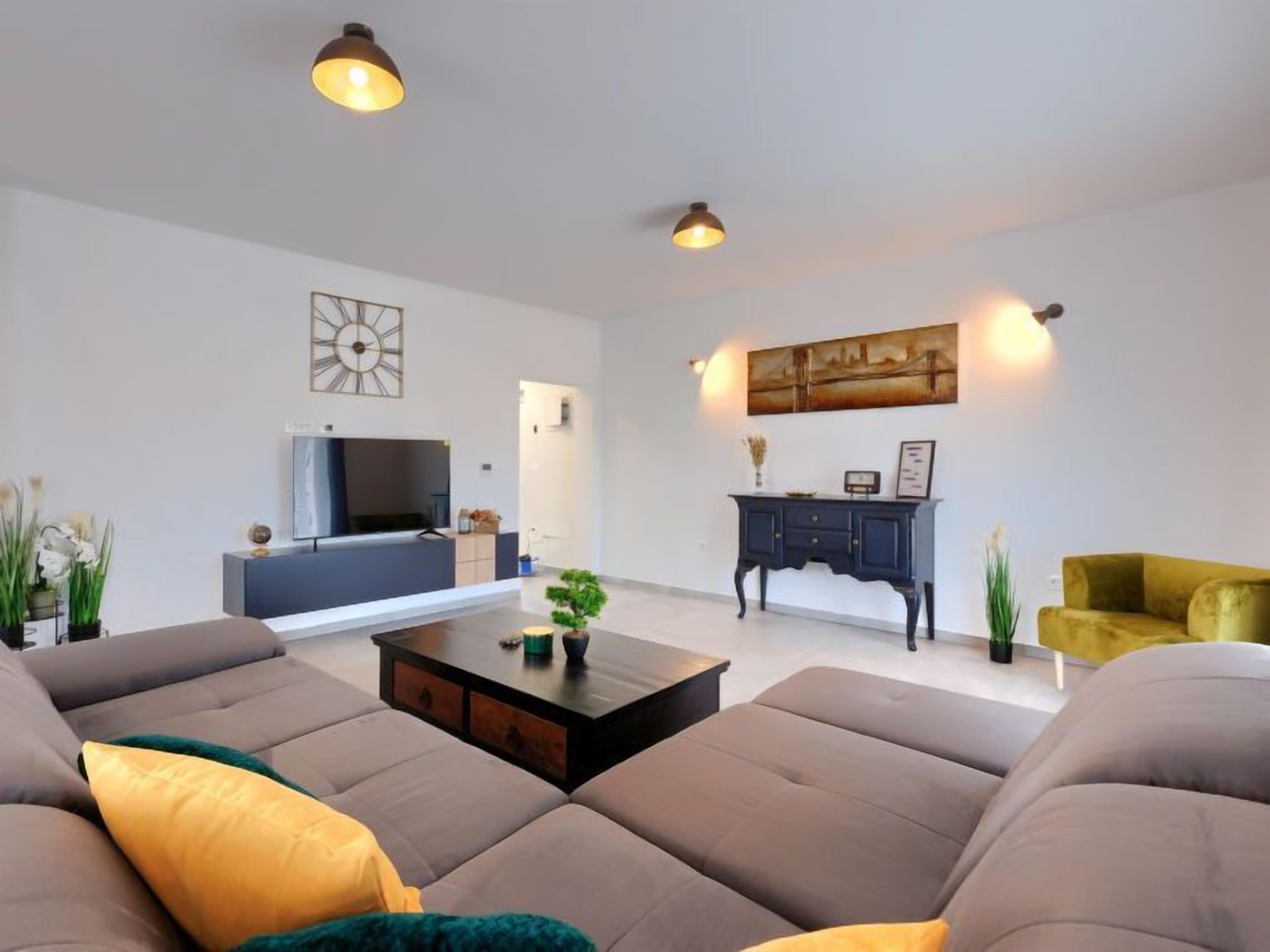 Uma sala de estar moderna com sofá, mesa de centro, televisão e armário.
