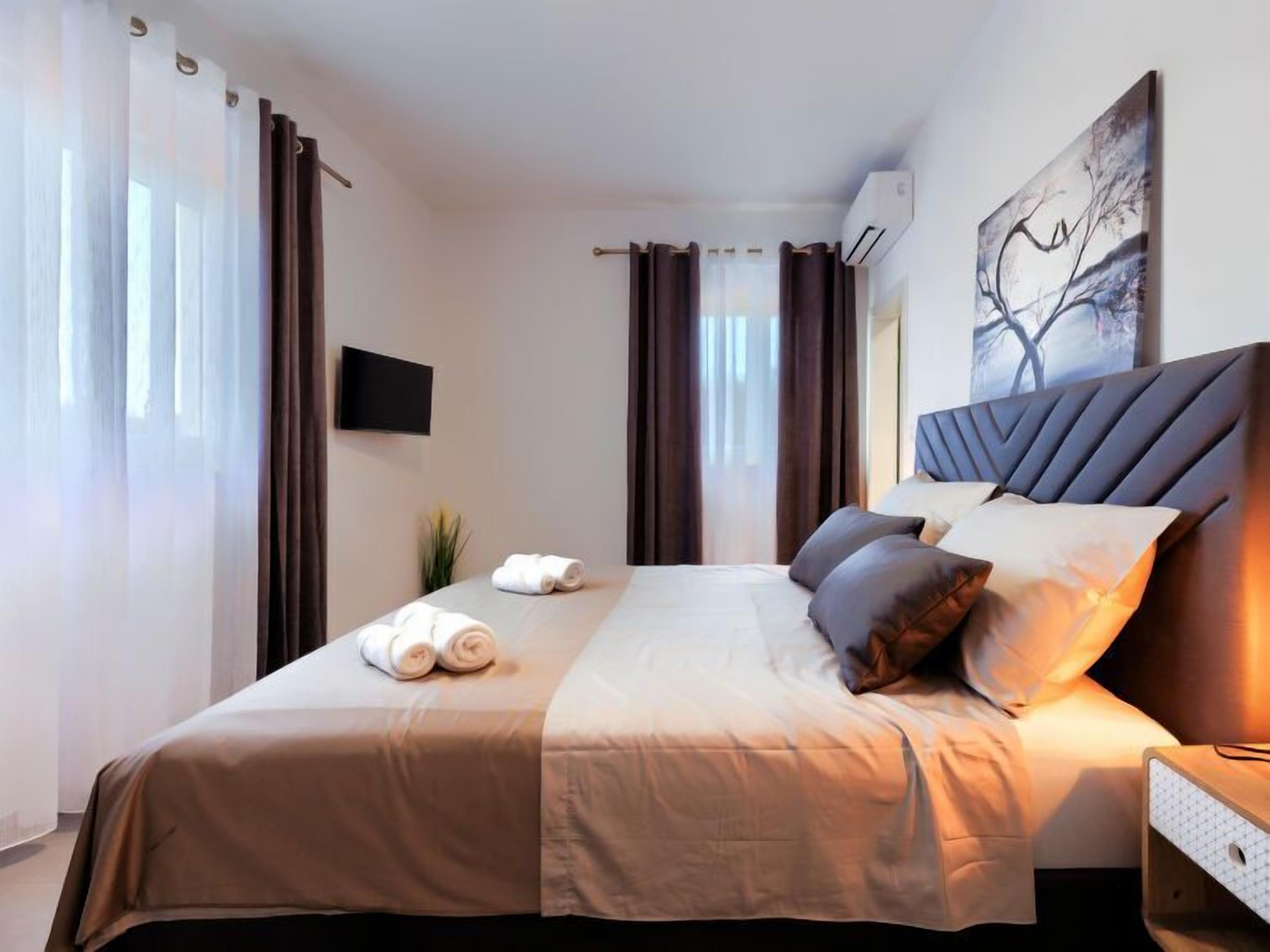 Una habitación de hotel con una cama grande, un televisor de pantalla plana y un cuadro en la pared.