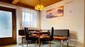 A dining area with a wooden table, two chairs, a bench, and a painting on the wall. - Gerlosblick by Interhome (Zell am Ziller)