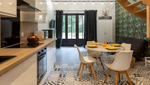 Une cuisine moderne avec un coin repas, comprenant un escalier, un téléviseur et une vue sur la verdure environnante.