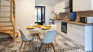 Une cuisine moderne avec des armoires blanches, un four à micro-ondes encastré et un coin repas comprenant une table ronde et deux chaises.