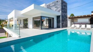 A modern house with a swimming pool, glass doors, and a patio area with lounge chairs. - La Haya by Interhome (Moraira)