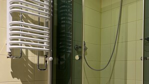 A glass-enclosed shower with a handheld showerhead and a white towel rack. - Garbarska 22 Aparthotel (Kraków)
