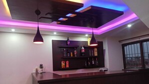 A modern bar area with a wooden counter, pendant lighting, and a shelf with bottles. - Hotel Royal Mantra (Kathmandu)