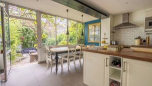 Une cuisine moderne avec un coin repas, de grandes fenêtres et une vue sur la verdure.