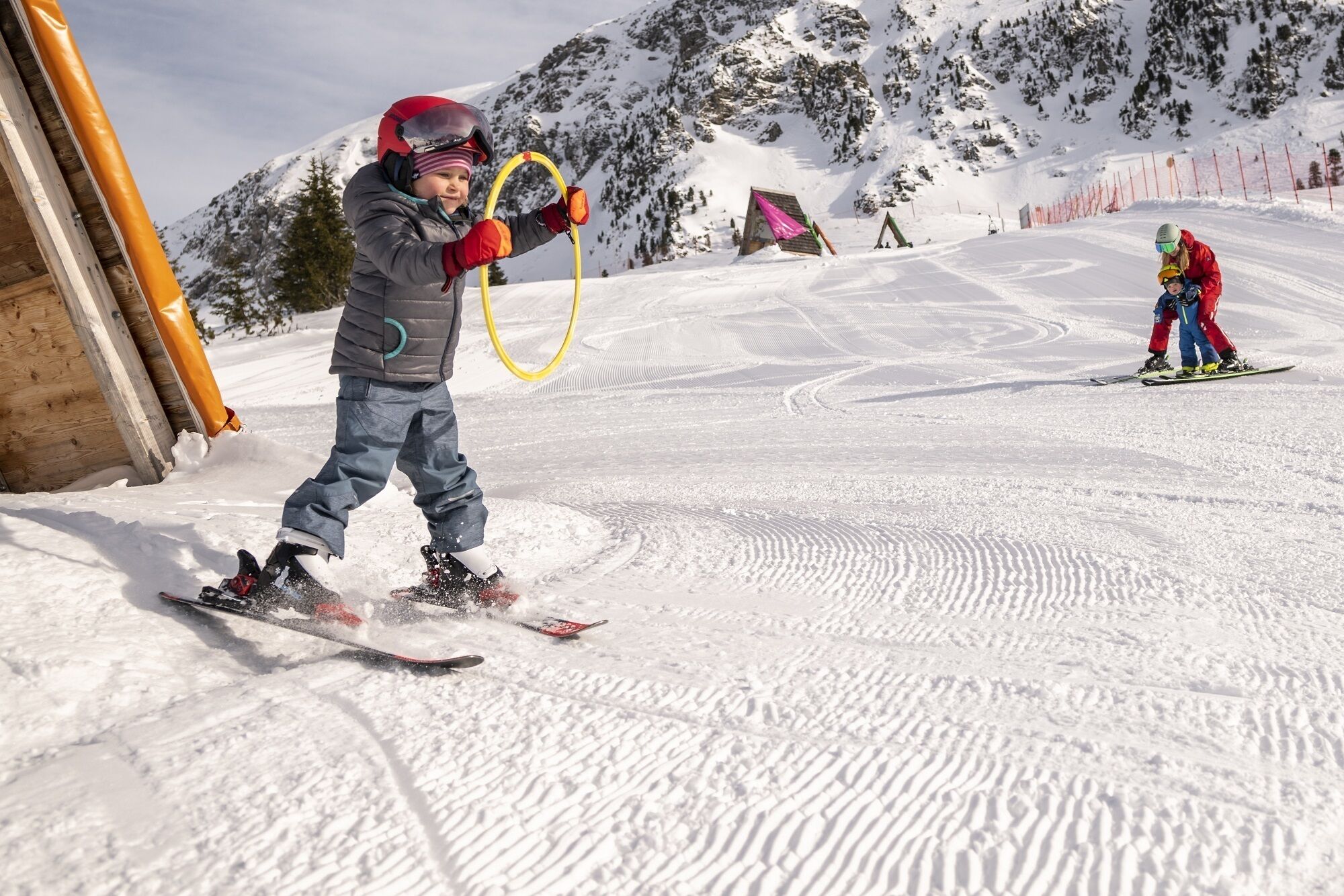 A child skiing on a snowy slope with a hula hoop.