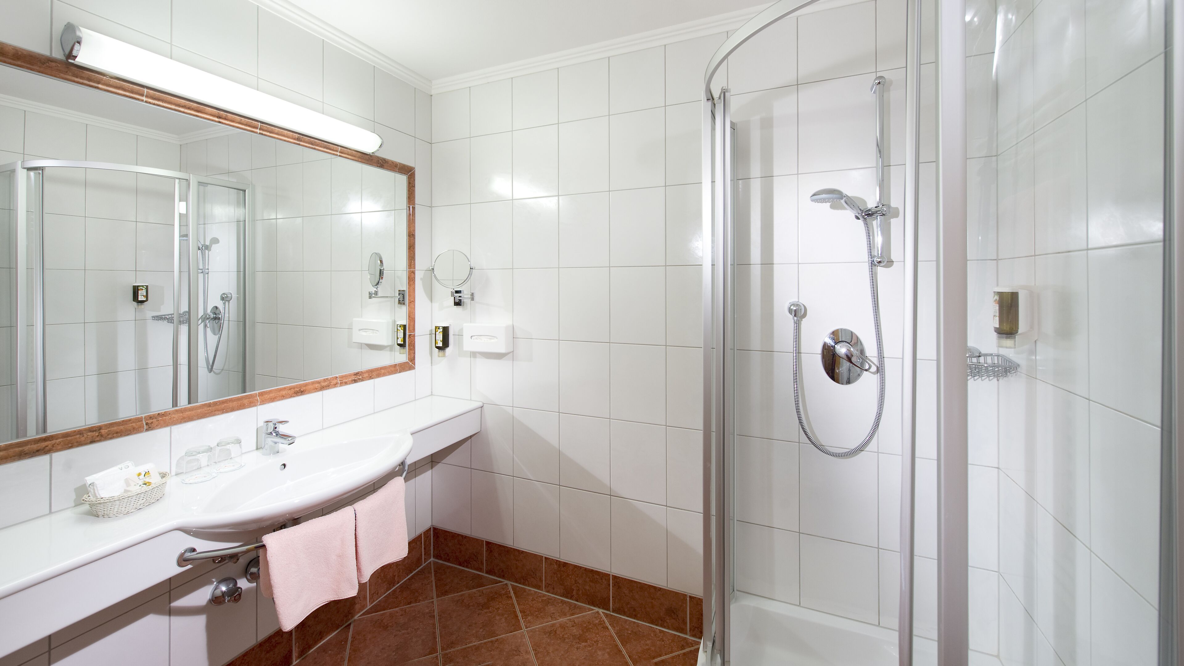 Un baño moderno con ducha envuelta en vidrio, un lavabo blanco y un espejo grande.