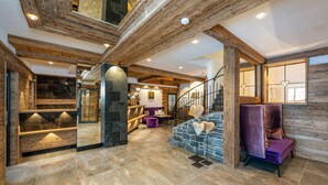 A spacious interior with a stone fireplace, wooden beams, and a staircase. - Hotel Zehnerkar & Hotel Obertauern (Tweng)