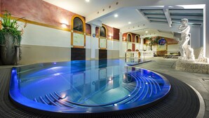 A modern indoor pool with a circular design, surrounded by a stone wall and a statue. - Hotel Zehnerkar & Hotel Obertauern (Tweng)