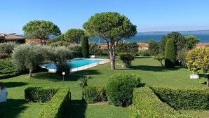 Un jardin bien entretenu, doté d’une piscine, de haies soigneusement taillées et de différentes espèces d’arbres.