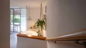 Une cuisine moderne avec un plan de travail blanc, des plantes suspendues et une vue sur la terrasse extérieure.