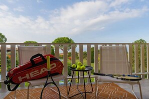 A balcony with a tennis racket, a red bag, and tennis balls.