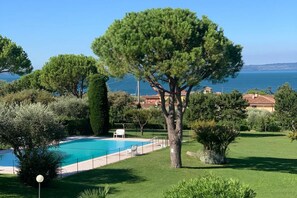 Ein Pool, umgeben von Grünflächen mit Blick auf das Meer.