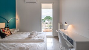 Une chambre avec un lit, un bureau et une vue sur le balcon extérieur.