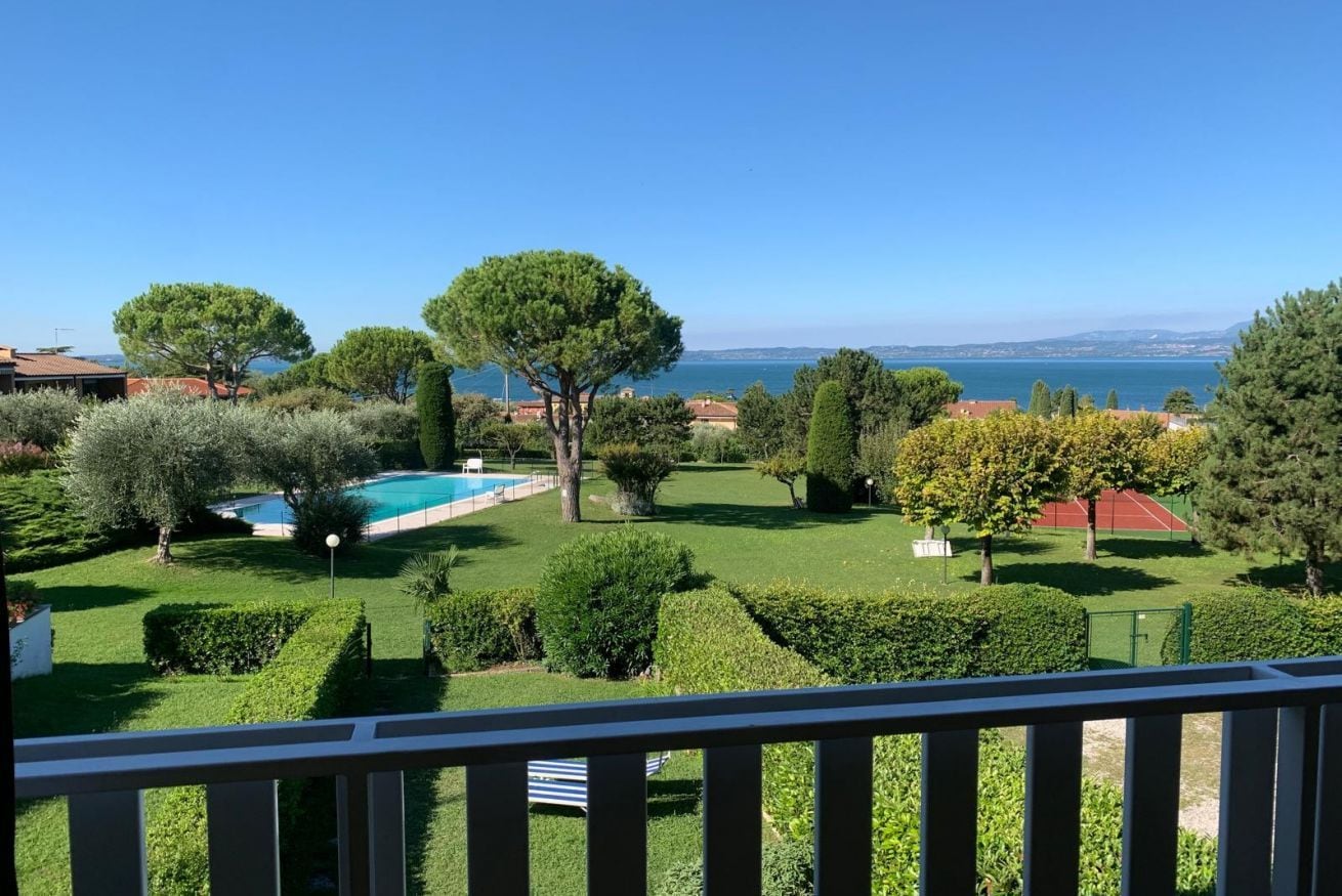 A well-maintained garden with a swimming pool, neatly trimmed hedges, and a tennis court.