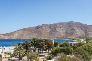 Un pueblo costero con una montaña al fondo, cielos despejados y vista al mar.