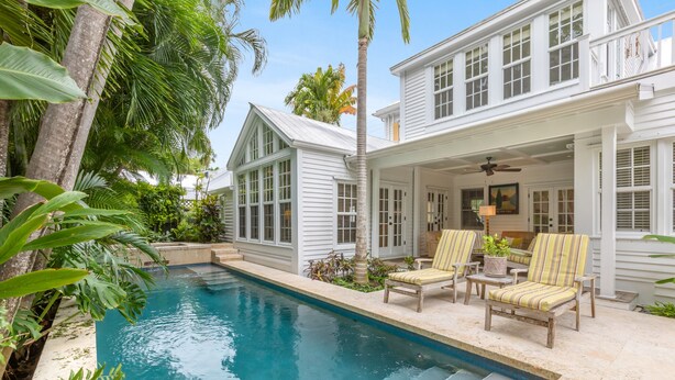 A poolside area with a pool, lounge chairs, and a covered patio. - BRIGHT SUNSHINY DAY ~ Renovated 3 BR, 4 Ba Home w/ Pool, Spa & Exercise Room! (Key West)