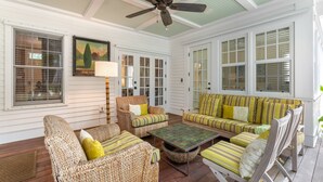 A covered porch with wicker furniture, a ceiling fan, and large windows. - BRIGHT SUNSHINY DAY ~ Renovated 3 BR, 4 Ba Home w/ Pool, Spa & Exercise Room! (Key West)