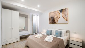 A modern bedroom with a bed, bedside tables, a wardrobe, a large abstract painting, and a sliding glass door. - Apartment "Dimora Idrusa" with Parking, Private Terrace, WiFi and Air Conditioning (Otranto)