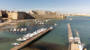 A harbor with boats docked, a pier extending into the water, and a fortified wall in the background. - Apartment "Dimora Idrusa" with Parking, Private Terrace, WiFi and Air Conditioning (Otranto)